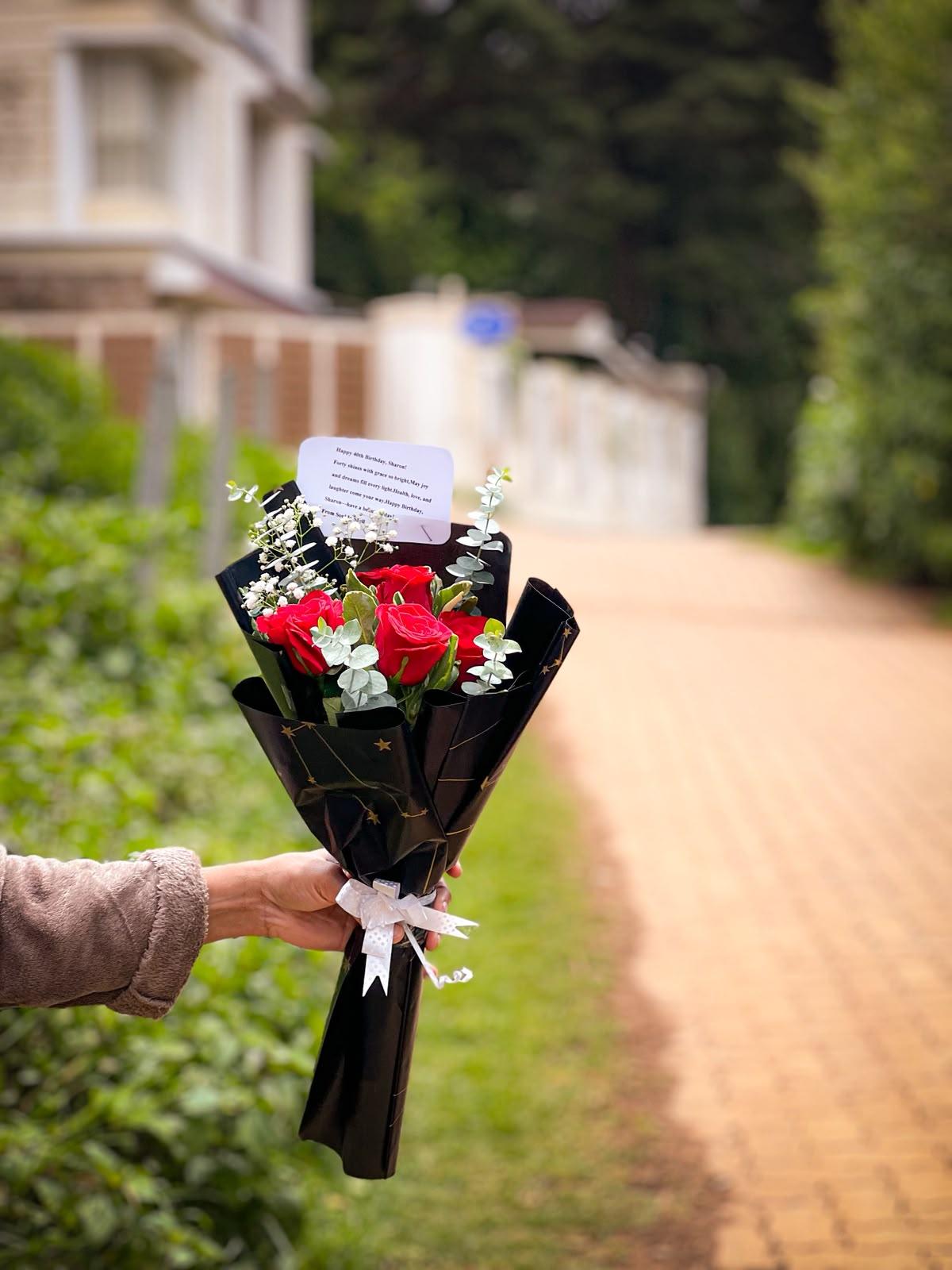 Fresh scarlet red roses wrapped in starry noir black wrap with personalized card in Ooty