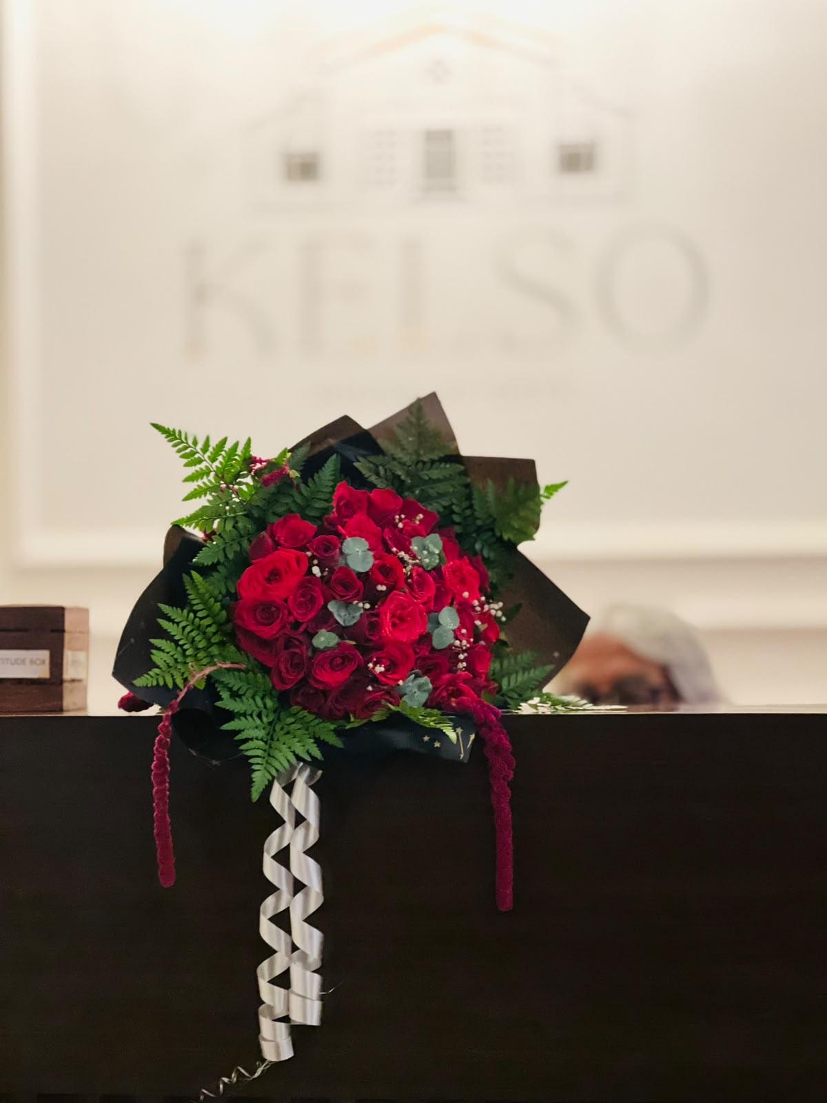 Dozens of rich scarlet red roses nestled in ferns and silver ribbon at an Ooty heritage salon