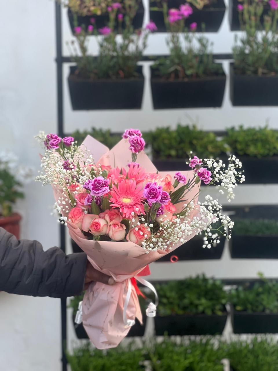 Pink gerbera, spray roses, purple carnations and baby breath in blush paper in Ooty