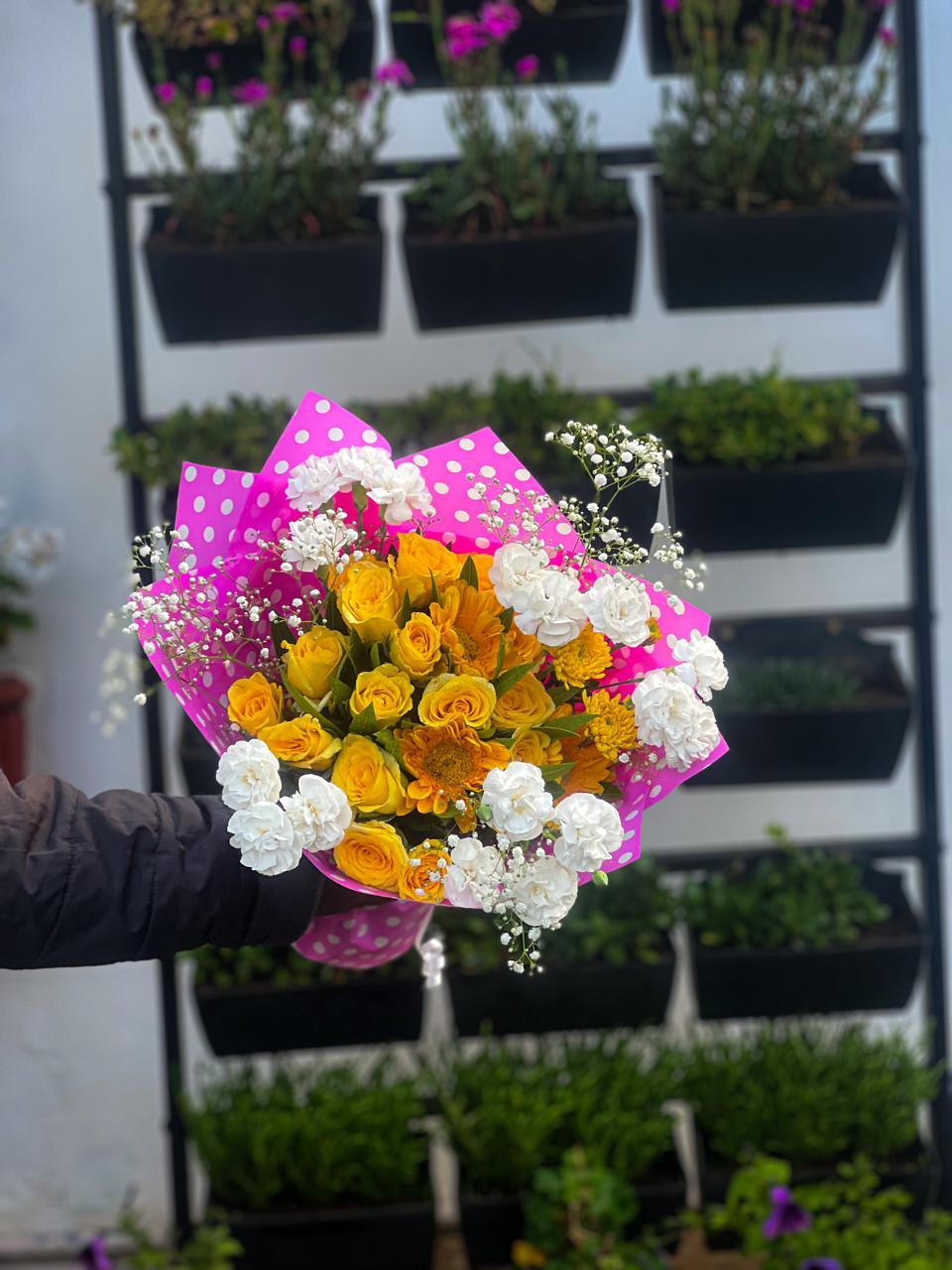Yellow roses, golden mums, and pure white carnations wrapped in playful pink polka wrap