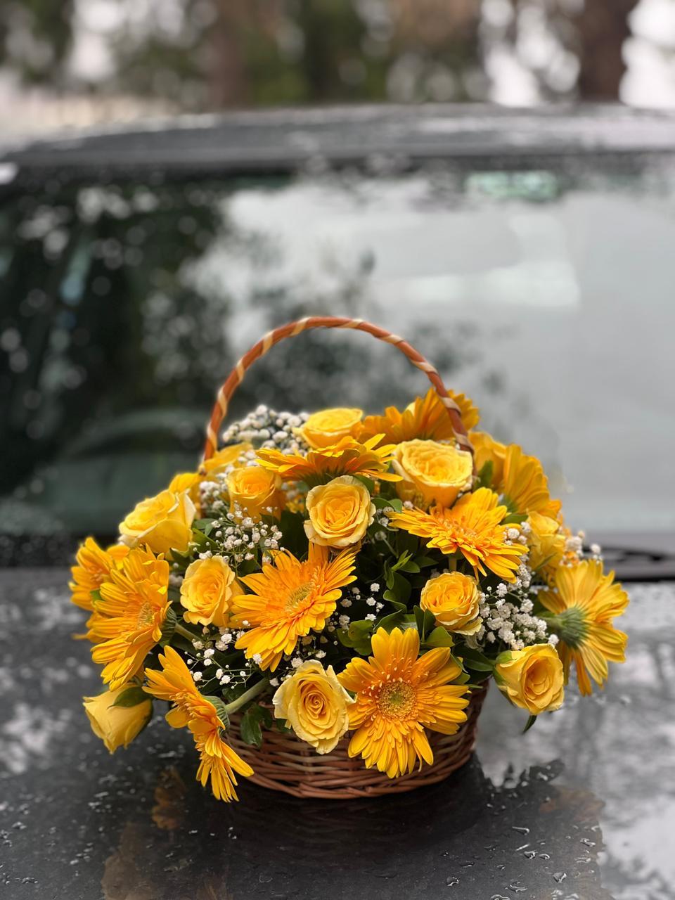 Woven cane basket filled with sunny yellow gerberas, tea roses and baby breath in Ooty