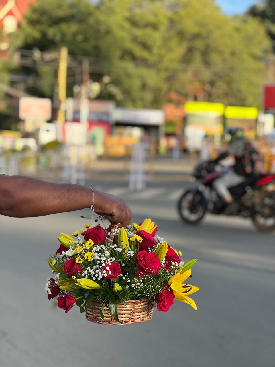 Fresh yellow Asiatic lilies and red roses arranged in a woven hand basket on Ooty roads