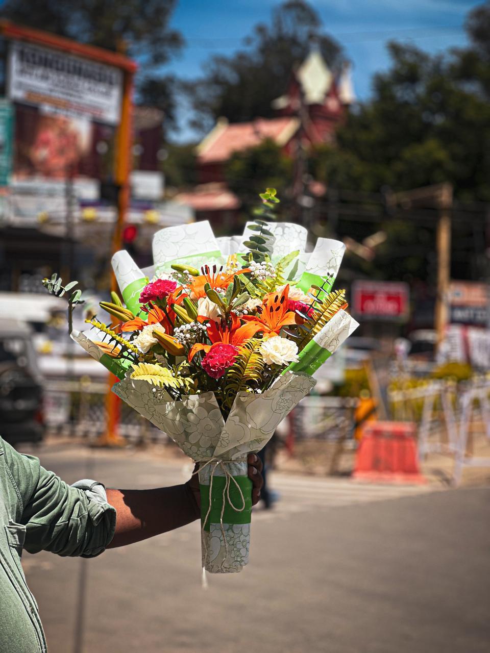 Dramatic tall bouquet of spotted orange Asiatic lilies, carnations and eucalyptus in Ooty